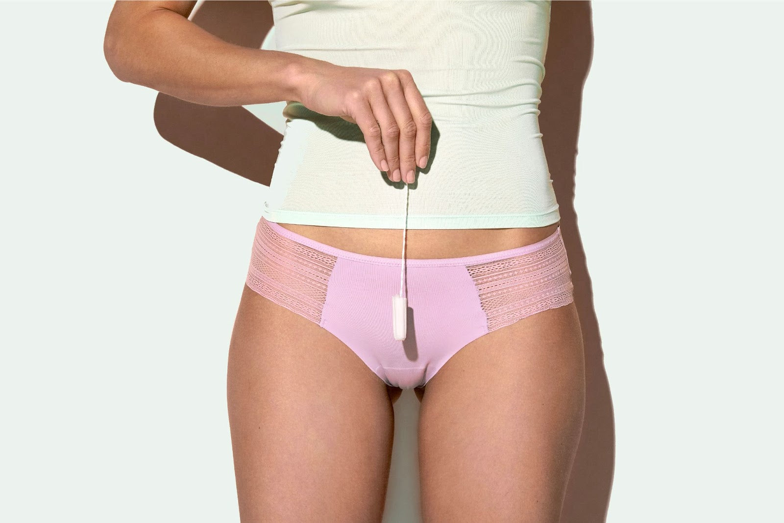 Woman wearing pink underwear holding a tampon.