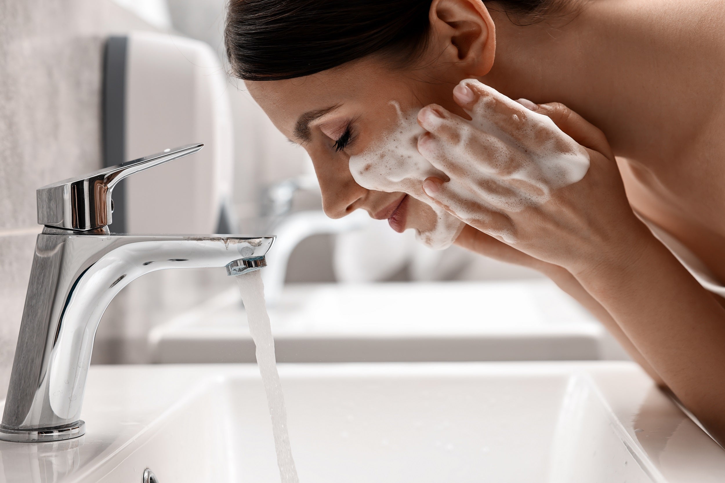 Woman washing face with a cleanser