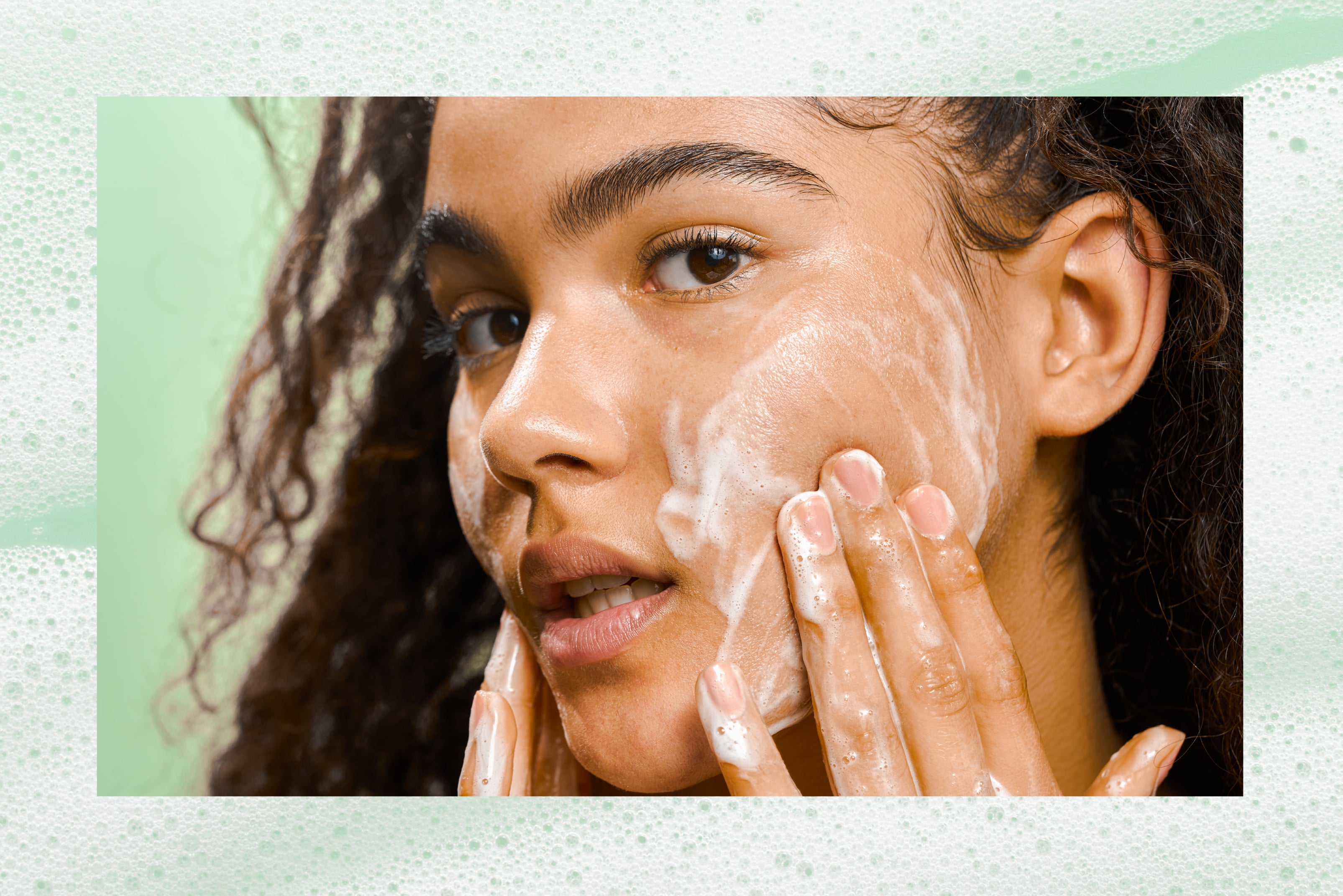 Close up of a woman washing her face after popping a pimple.