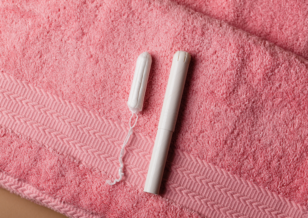 A tampon removed from its casing on a pink beach towel.