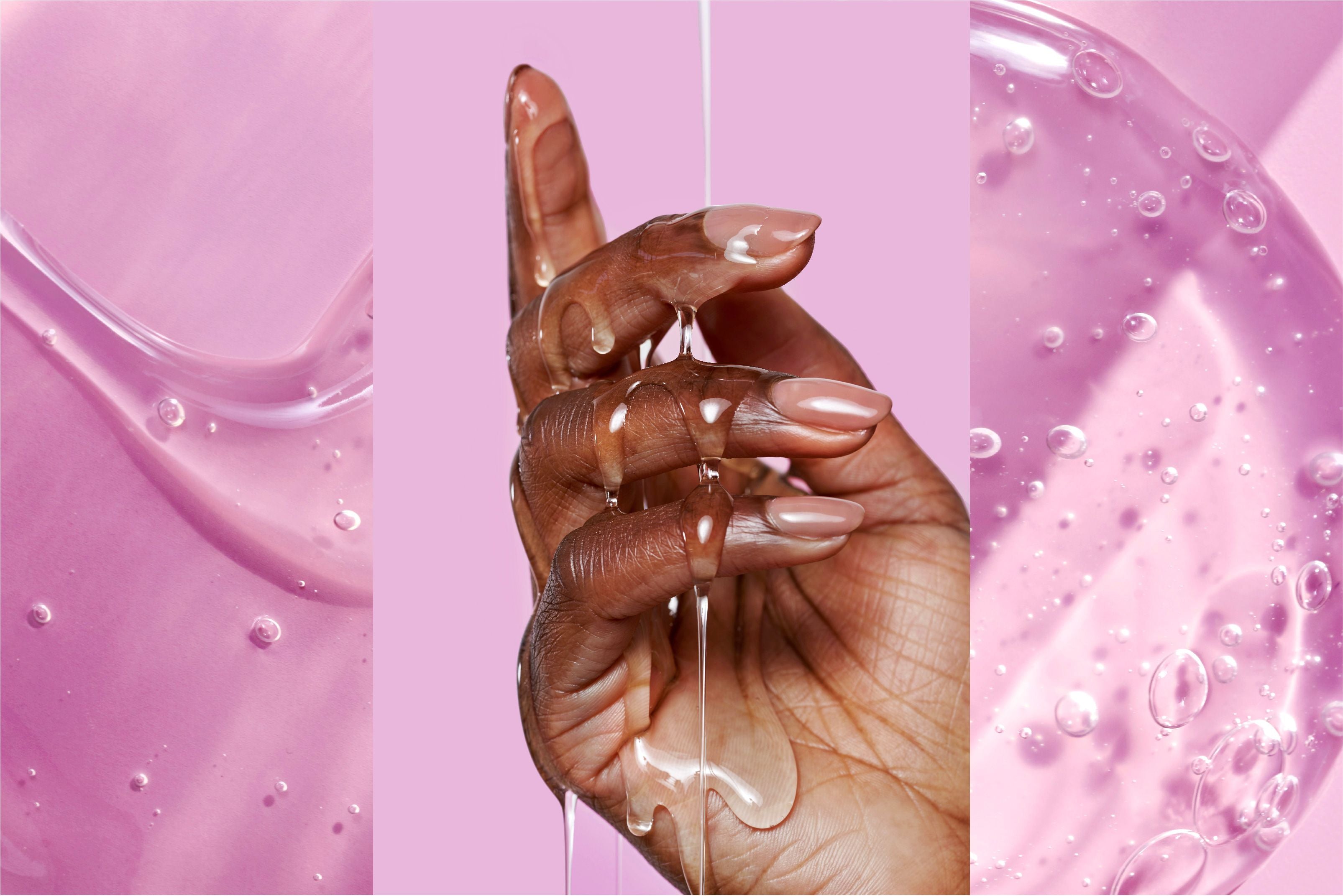 Close up of clear fluid running over a woman's hand against a pink background.