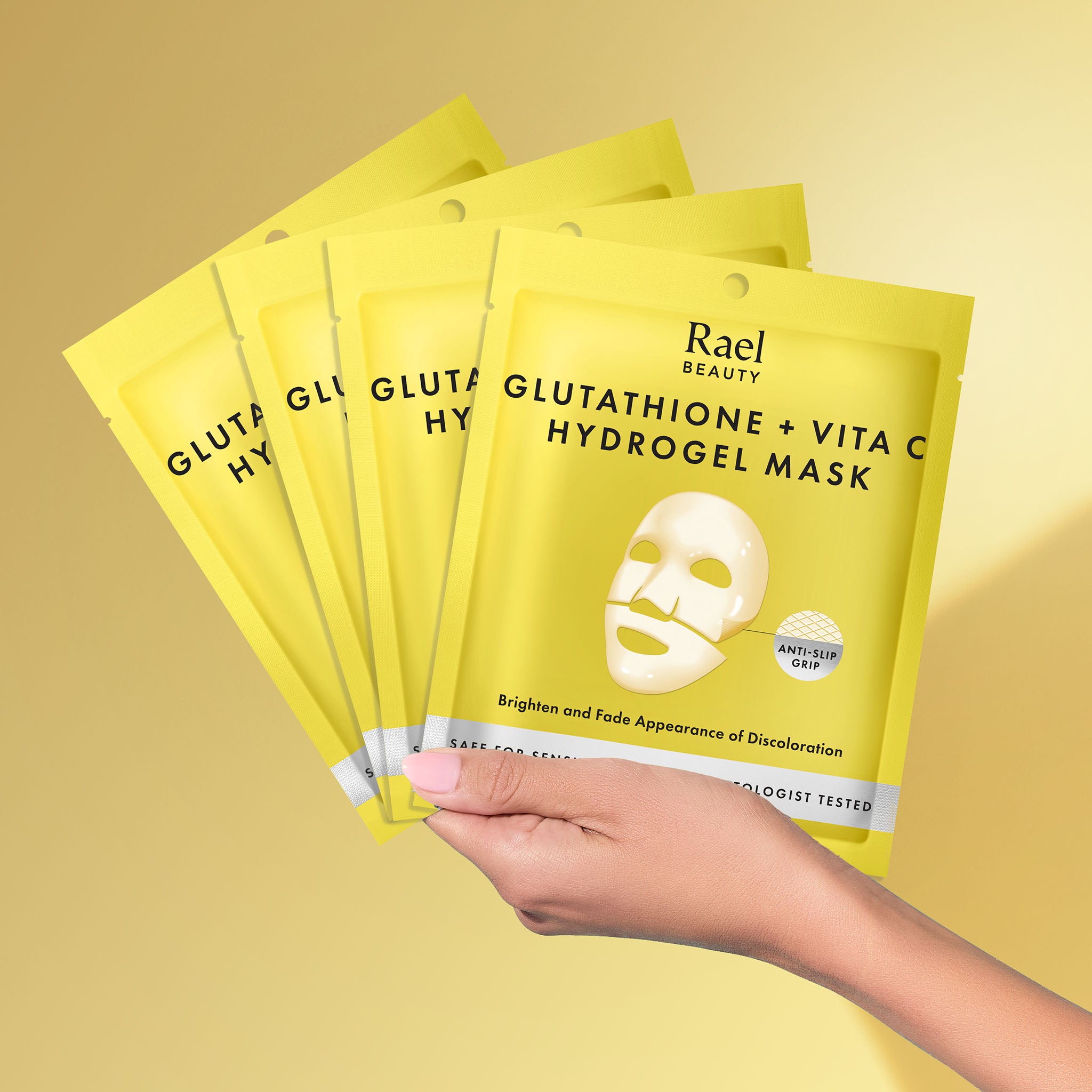 Hand holding Rael Beauty Glutathione + Vita C Hydrogel Mask packages on a yellow background